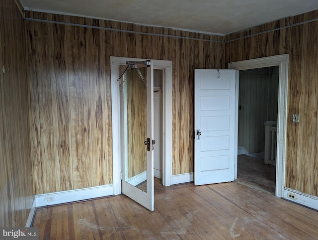 unfurnished bedroom featuring wood walls and hardwood / wood-style flooring