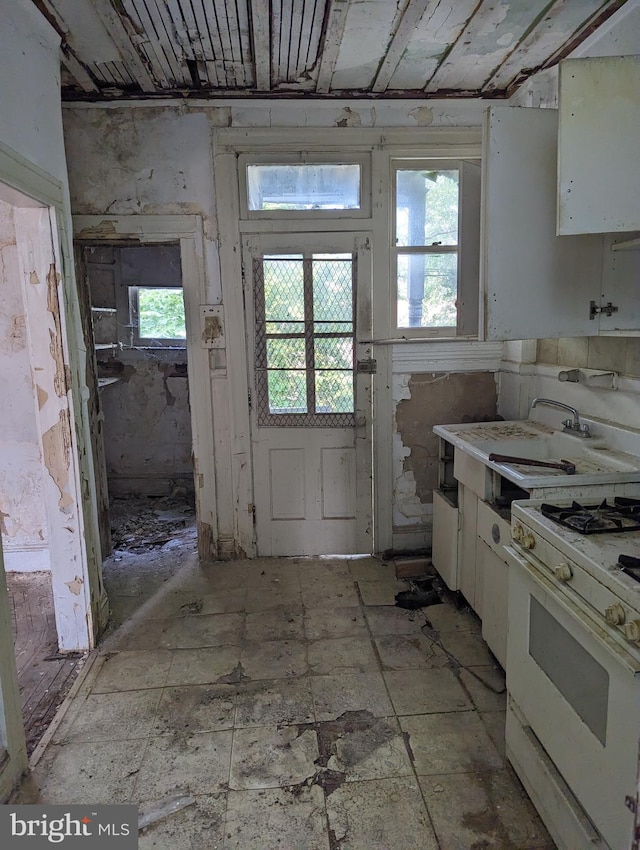 kitchen featuring white cabinetry, white range with gas stovetop, and sink