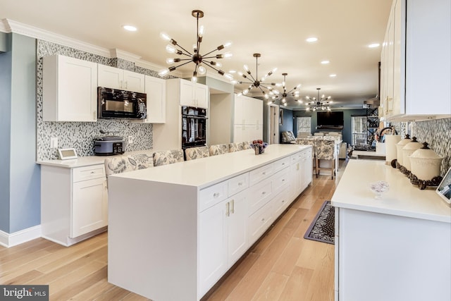 kitchen featuring a chandelier, white cabinetry, a kitchen island, and black appliances