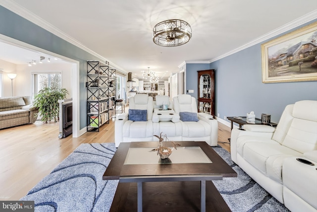 living room with light hardwood / wood-style floors, crown molding, and a notable chandelier