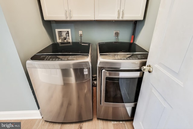 laundry area featuring cabinets, separate washer and dryer, and light hardwood / wood-style flooring