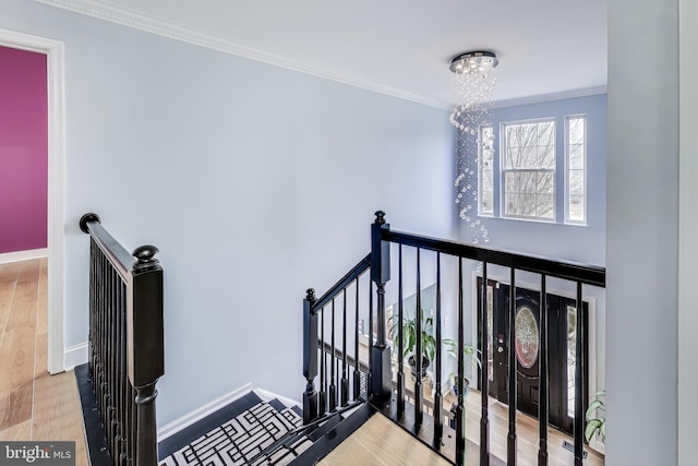 stairs featuring crown molding, a chandelier, and hardwood / wood-style flooring