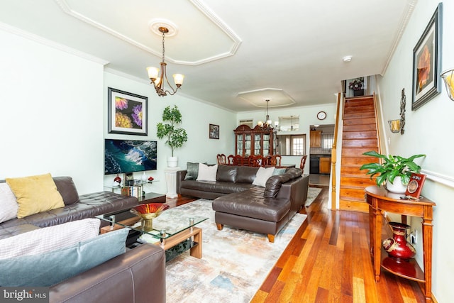 living room featuring wood-type flooring, crown molding, and a notable chandelier