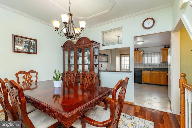 dining area with sink, ornamental molding, dark hardwood / wood-style floors, and a notable chandelier