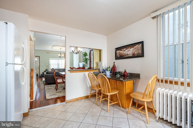 dining area featuring radiator heating unit, light tile patterned flooring, and a chandelier