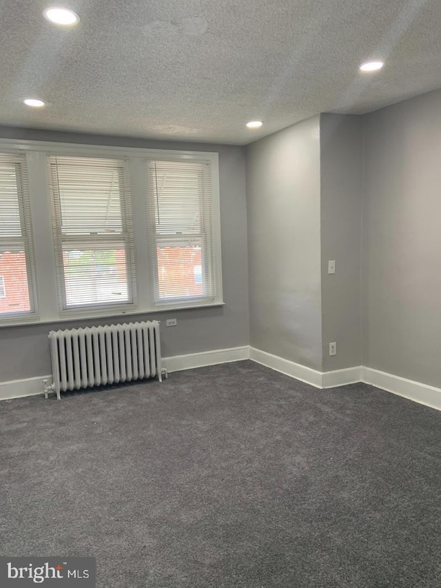 unfurnished room with a textured ceiling and radiator