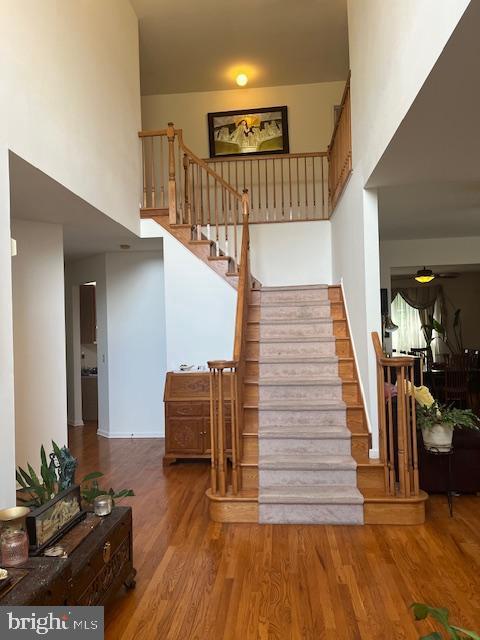 stairs with hardwood / wood-style floors and a high ceiling