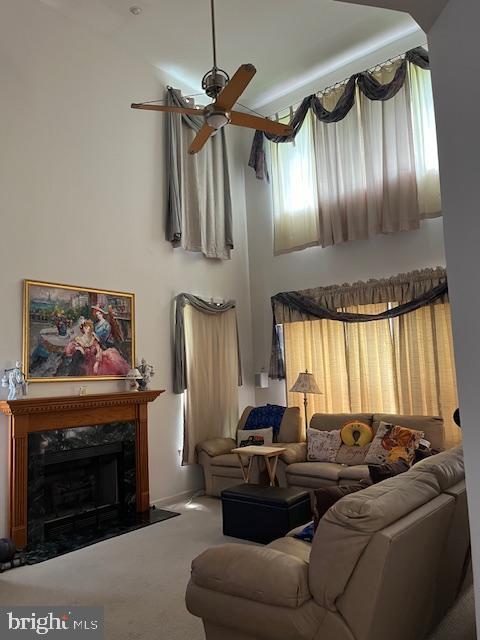 carpeted living room featuring ceiling fan and a fireplace