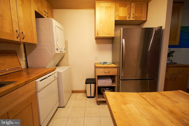 kitchen featuring white dishwasher, stainless steel fridge, light tile patterned floors, and wooden counters