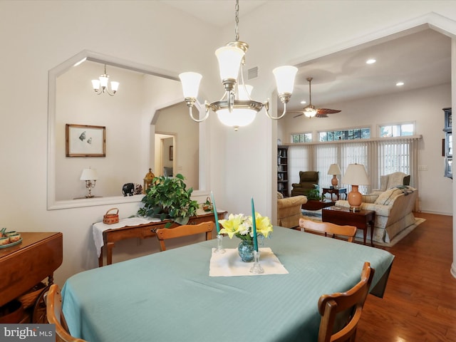 dining space featuring ceiling fan with notable chandelier and wood-type flooring