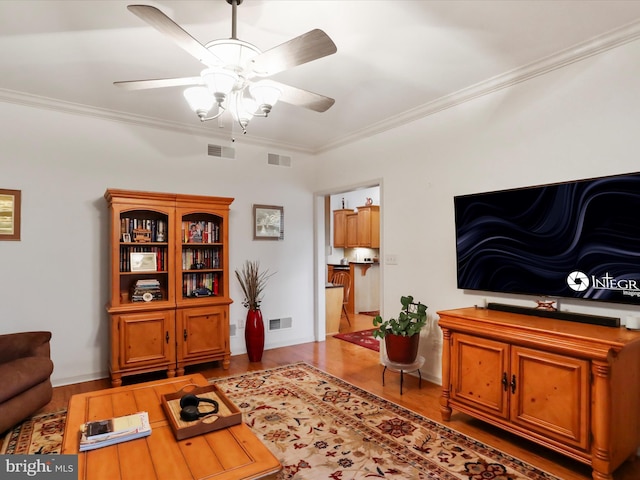 living room with ceiling fan, crown molding, and wood-type flooring