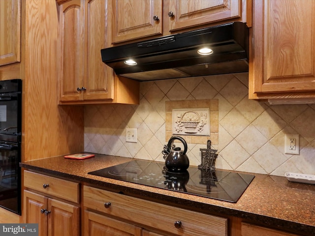 kitchen featuring black appliances, dark stone counters, and tasteful backsplash