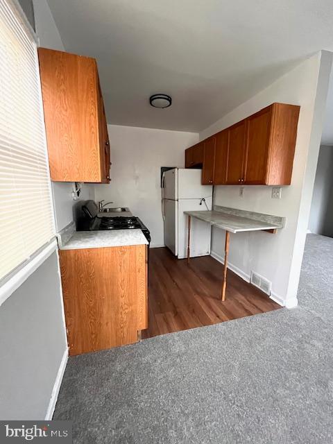 kitchen with white fridge and dark carpet