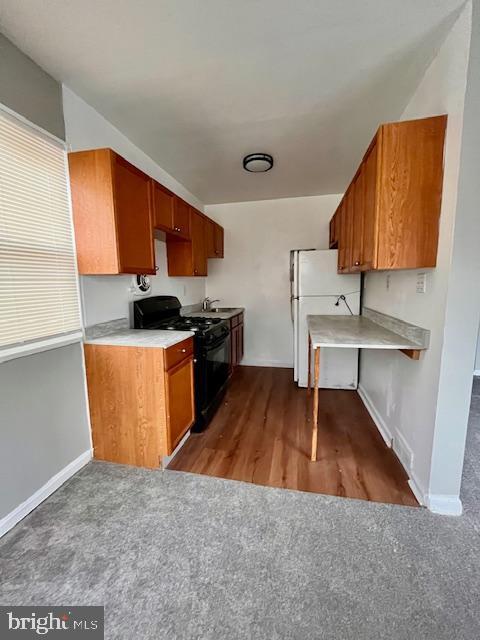 kitchen featuring carpet, sink, black range, and white fridge