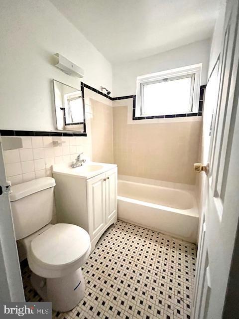 full bathroom featuring vanity, toilet, tile walls, and tiled shower / bath combo