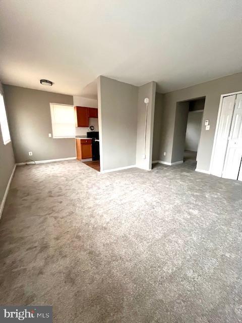 unfurnished living room with carpet and baseboards