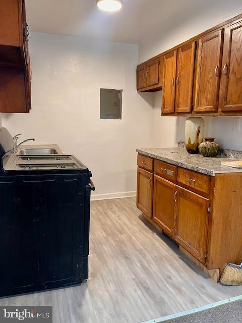 kitchen featuring electric panel, light hardwood / wood-style flooring, and black / electric stove