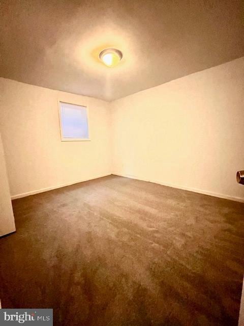 unfurnished room with dark carpet