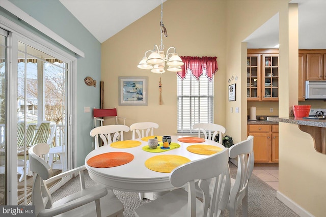 dining area featuring light tile patterned flooring, lofted ceiling, and an inviting chandelier