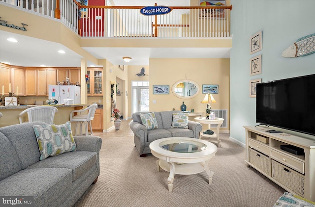 living room with a towering ceiling and light carpet