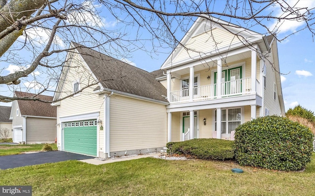 view of front of home with a balcony, a front yard, and a garage