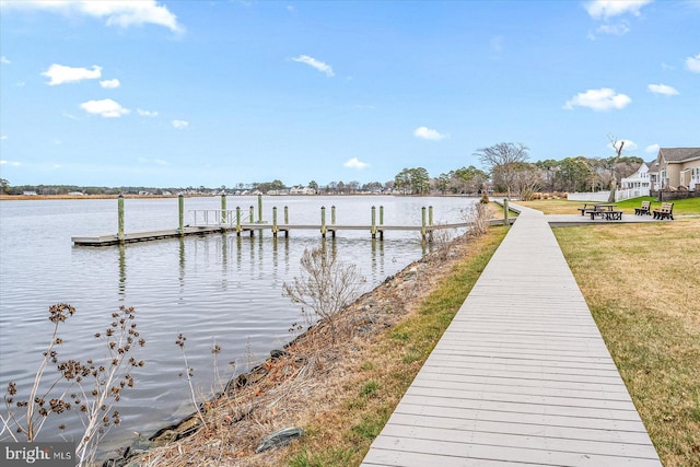 view of dock with a water view and a lawn