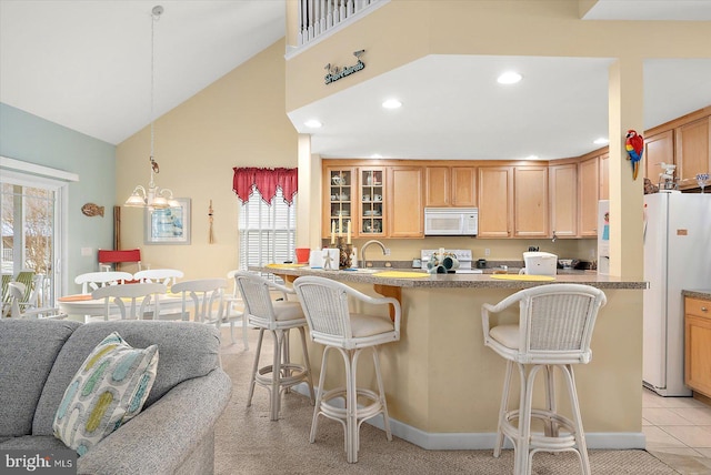 kitchen featuring pendant lighting, white appliances, a kitchen breakfast bar, light tile patterned floors, and kitchen peninsula