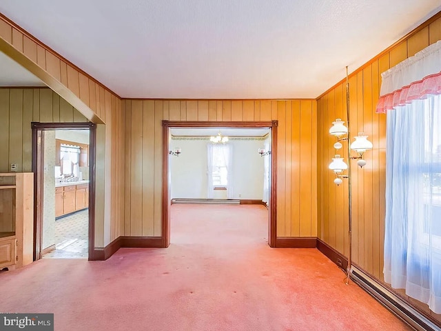 hall featuring carpet flooring, a baseboard radiator, and wooden walls