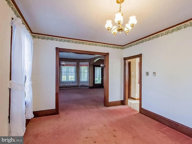 carpeted spare room featuring plenty of natural light, ornamental molding, and a notable chandelier