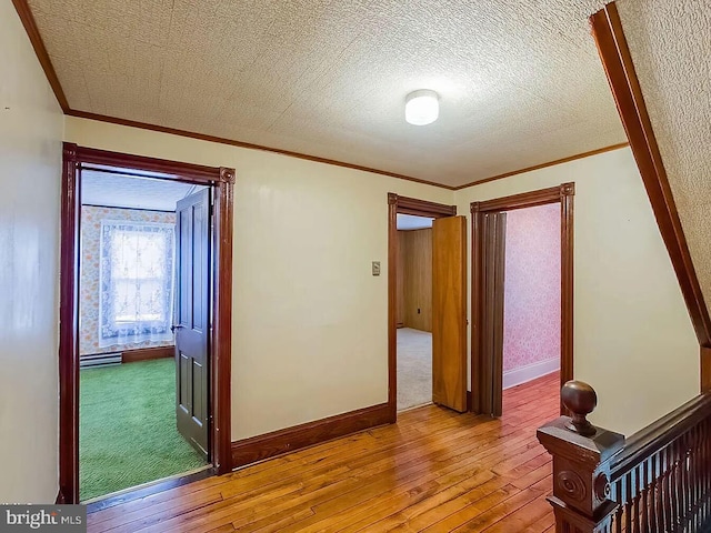 hall with ornamental molding, a textured ceiling, and light hardwood / wood-style flooring