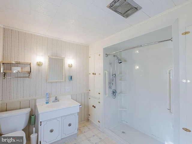 bathroom featuring a shower, vanity, toilet, and ornamental molding