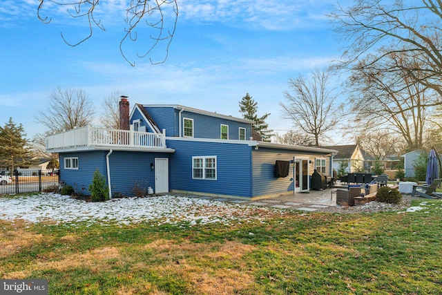 back of property with a lawn, a balcony, and a patio