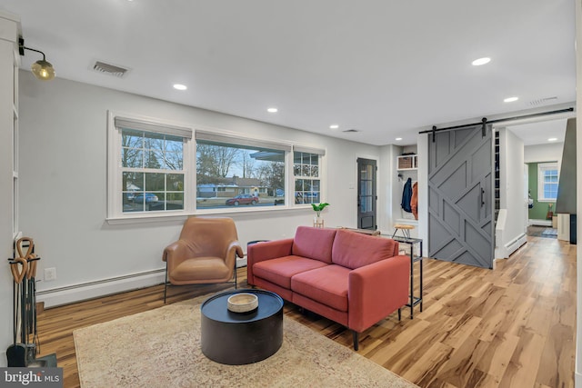 living room featuring a barn door, a baseboard radiator, and light hardwood / wood-style flooring