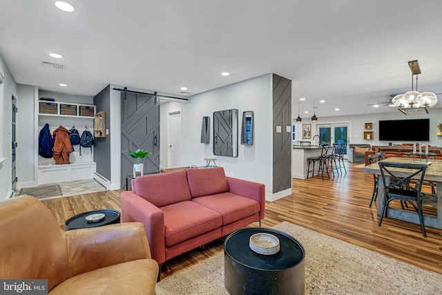 living room featuring hardwood / wood-style floors, a barn door, a baseboard radiator, and an inviting chandelier