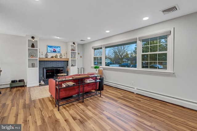 living room with a brick fireplace, light hardwood / wood-style flooring, and baseboard heating