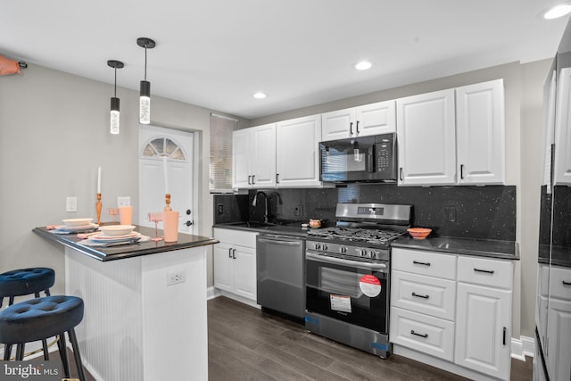 kitchen with kitchen peninsula, appliances with stainless steel finishes, tasteful backsplash, sink, and white cabinetry