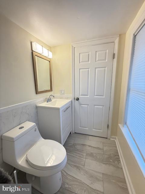 bathroom featuring vanity, tile walls, and toilet