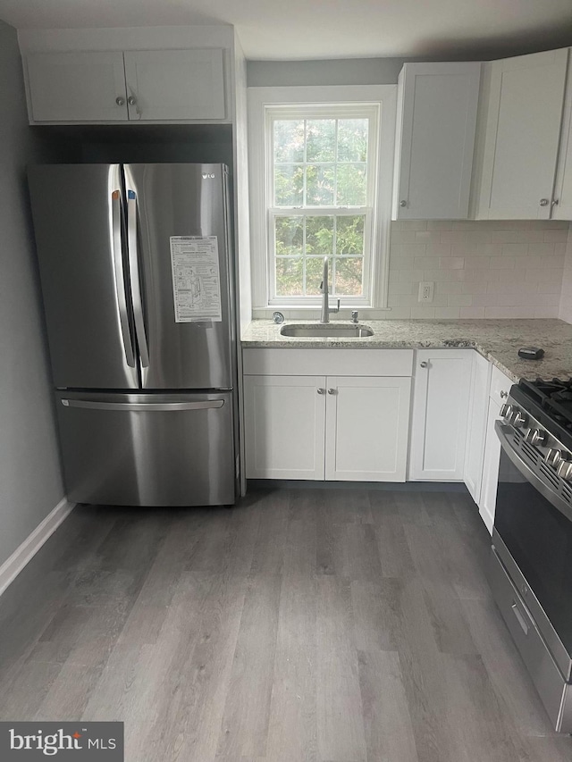 kitchen with sink, white cabinets, decorative backsplash, light stone counters, and stainless steel appliances