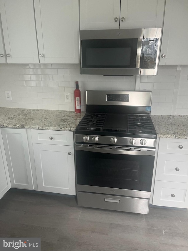 kitchen with backsplash, appliances with stainless steel finishes, light stone countertops, and white cabinets