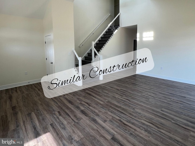 unfurnished living room with dark hardwood / wood-style flooring and a high ceiling