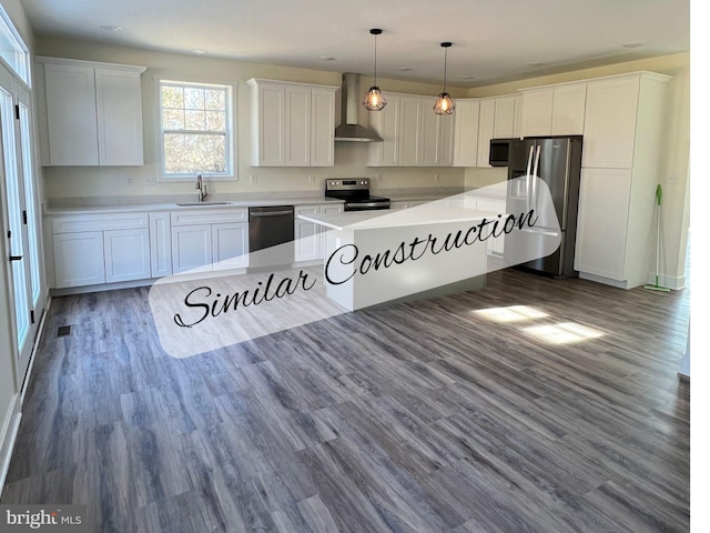 kitchen with pendant lighting, white cabinetry, sink, stainless steel appliances, and wall chimney exhaust hood