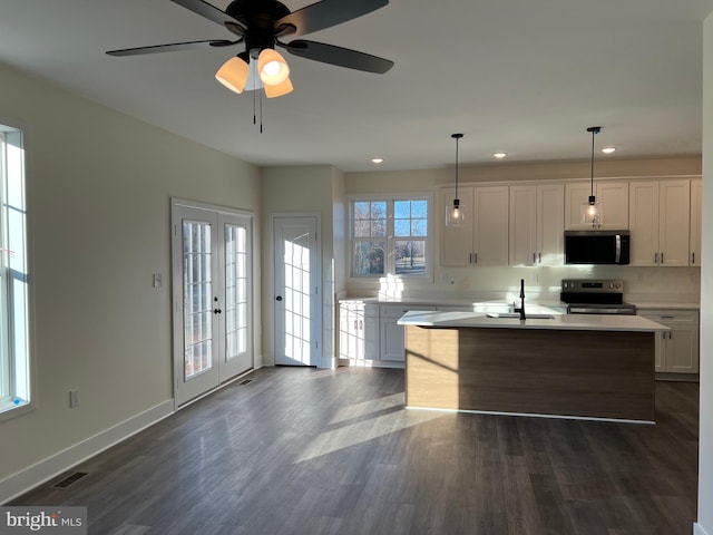 kitchen featuring pendant lighting, sink, stainless steel appliances, an island with sink, and white cabinets