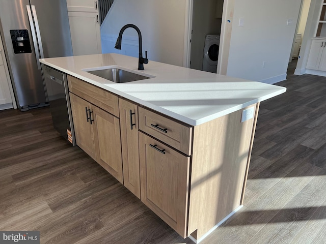 kitchen featuring appliances with stainless steel finishes, washer / clothes dryer, sink, dark hardwood / wood-style flooring, and a kitchen island with sink