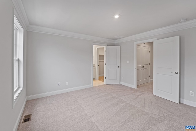 unfurnished bedroom featuring a spacious closet, multiple windows, and crown molding