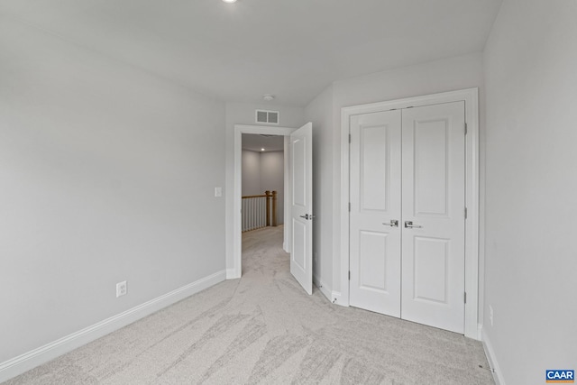 unfurnished bedroom featuring light carpet and a closet