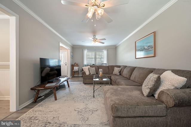 living area with ornamental molding, a ceiling fan, baseboards, and wood finished floors