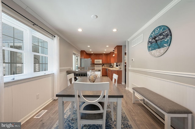 dining room with visible vents, crown molding, and wood finished floors