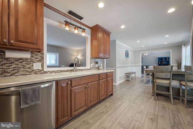 kitchen featuring dishwasher, light wood-style flooring, ornamental molding, light countertops, and a sink