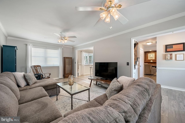 living area with light wood-style floors, ornamental molding, baseboards, and ceiling fan