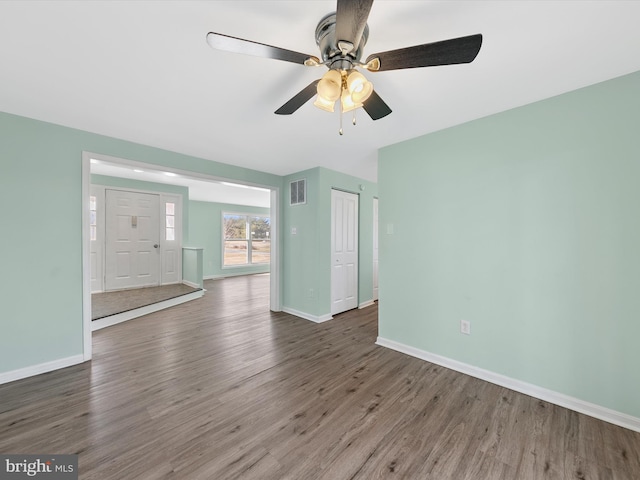 empty room with ceiling fan and dark wood-type flooring